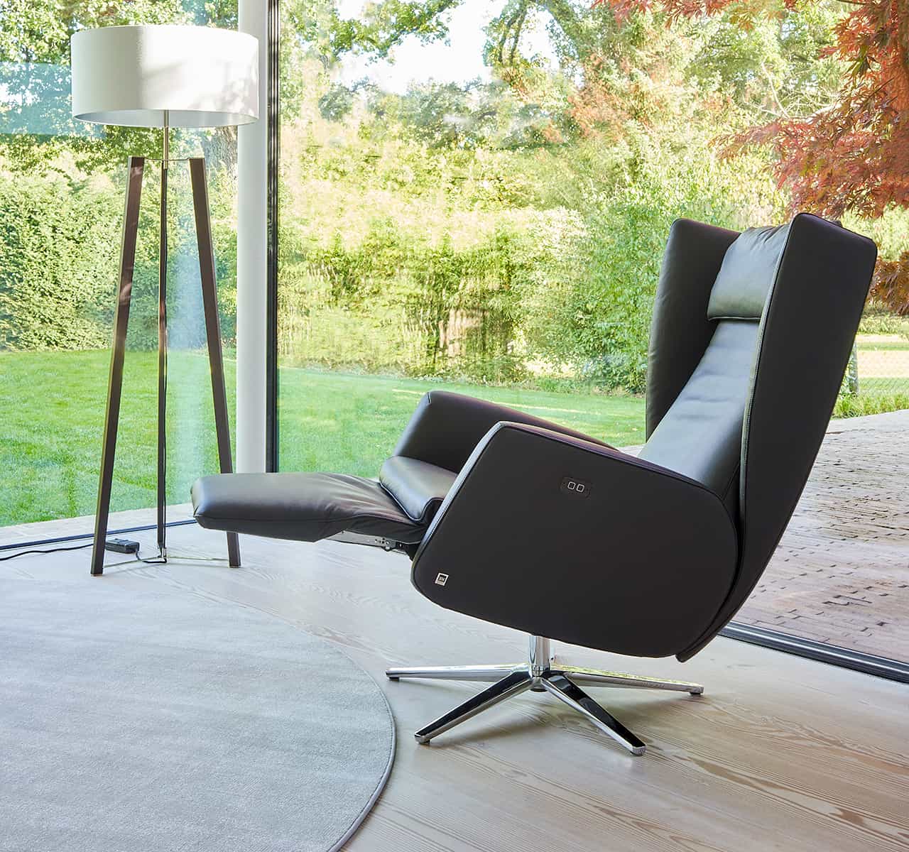 Moderner Relaxsessel mit verstellbarer Fußlehne, der entspanntes Zurücklehnen mit Blick ins Grüne ermöglicht